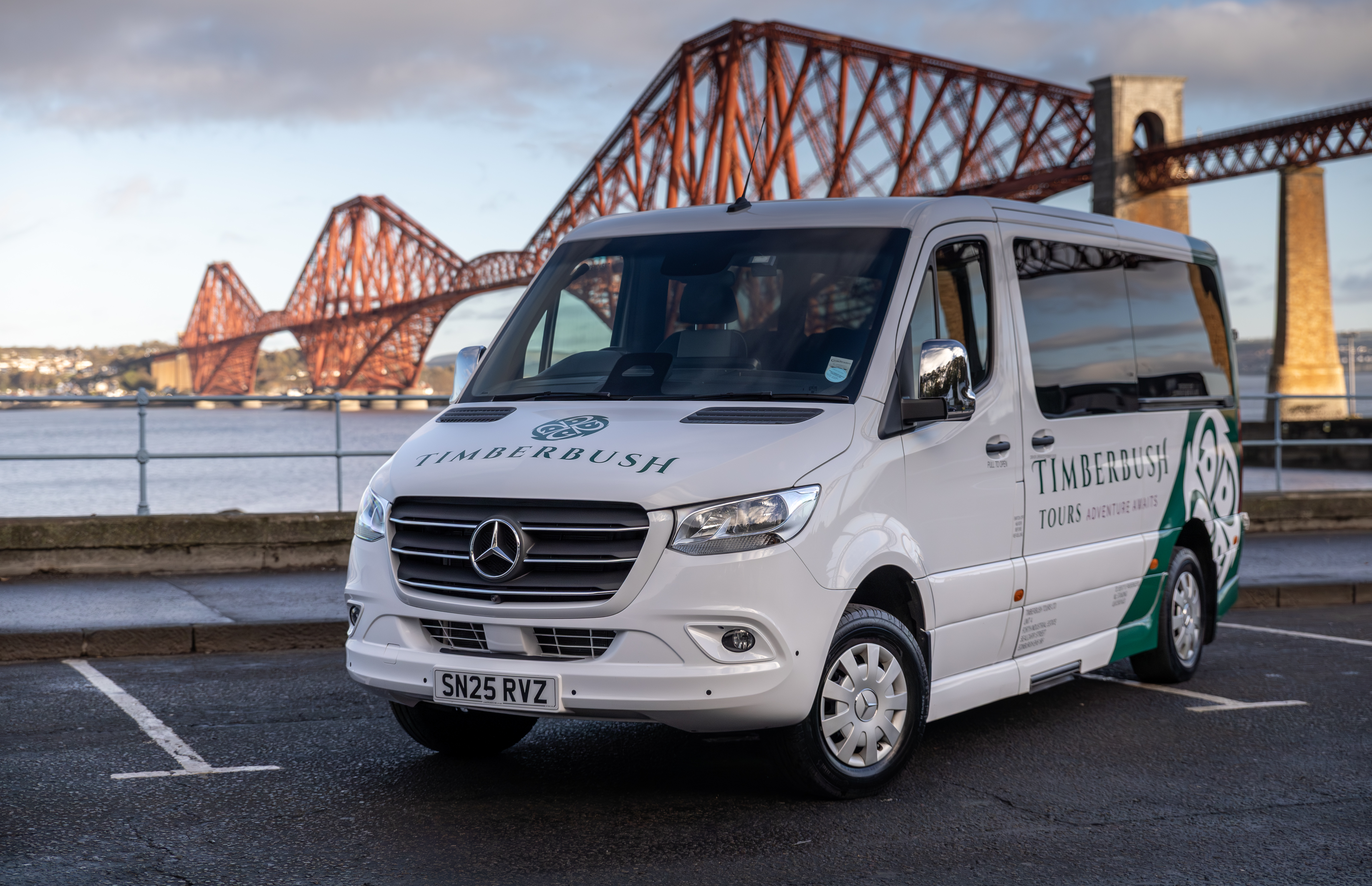A touring coach with the Forth Bridge in the background.